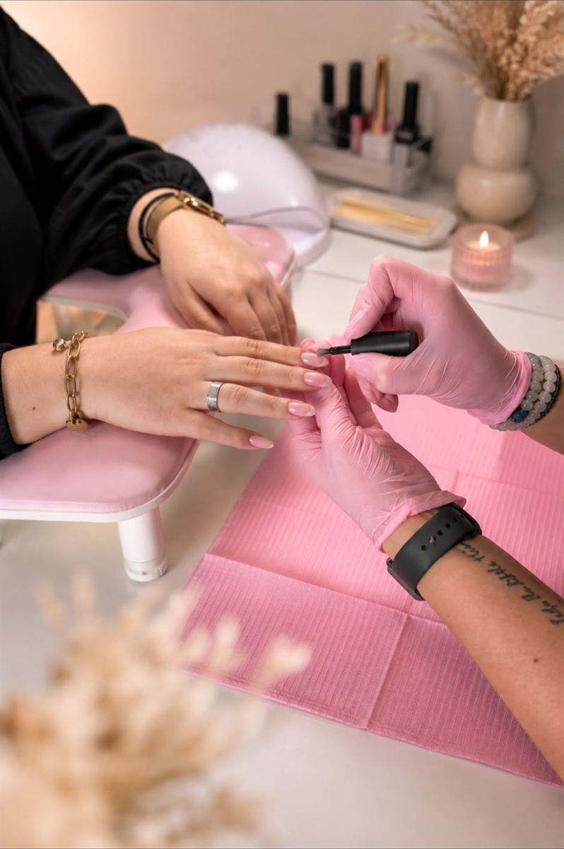 Behandeling in de salon: gellak wordt aangebracht aan een roze tafel